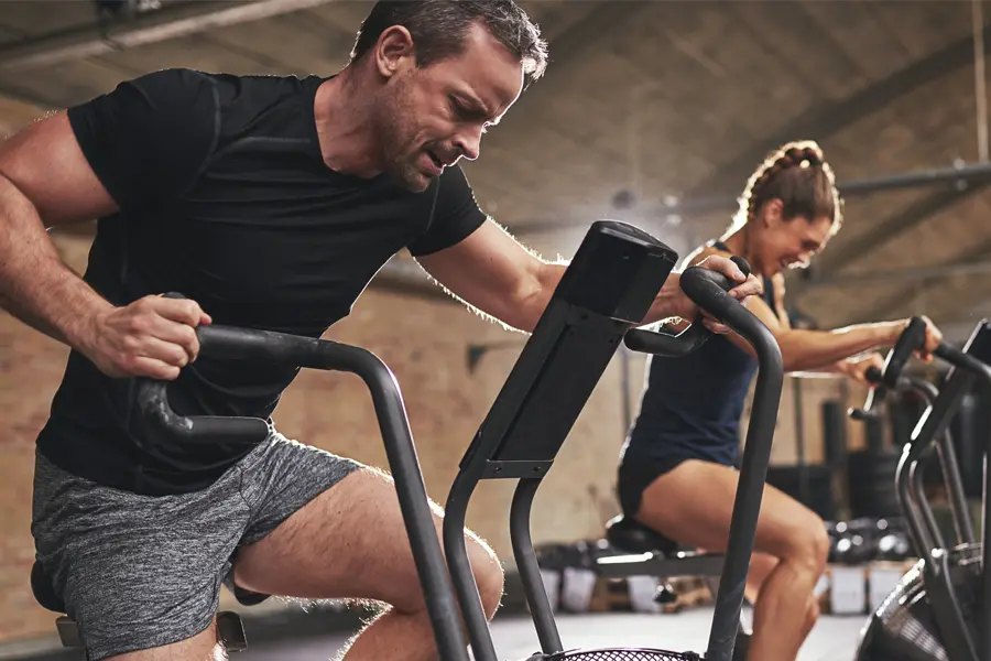 Tirzepatide-Doctor A couple in a brick gym work as hard as they can on exercise bikes, inspired by successful Tirzepatide treatment from Healthy Aging Medical Centers of New Jersey in Northern New Jersey.