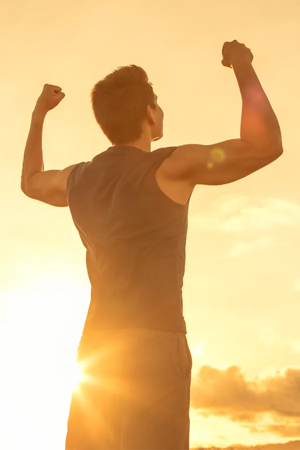 Wegovy-Weight-Loss-Treatment A motivational image of a young man standing with his back to the camera, arms raised triumphantly against a sunrise. Representing Wegovy Weight Loss Injections offered by Healthy Aging Medical Centers of New Jersey in Northern New Jersey.